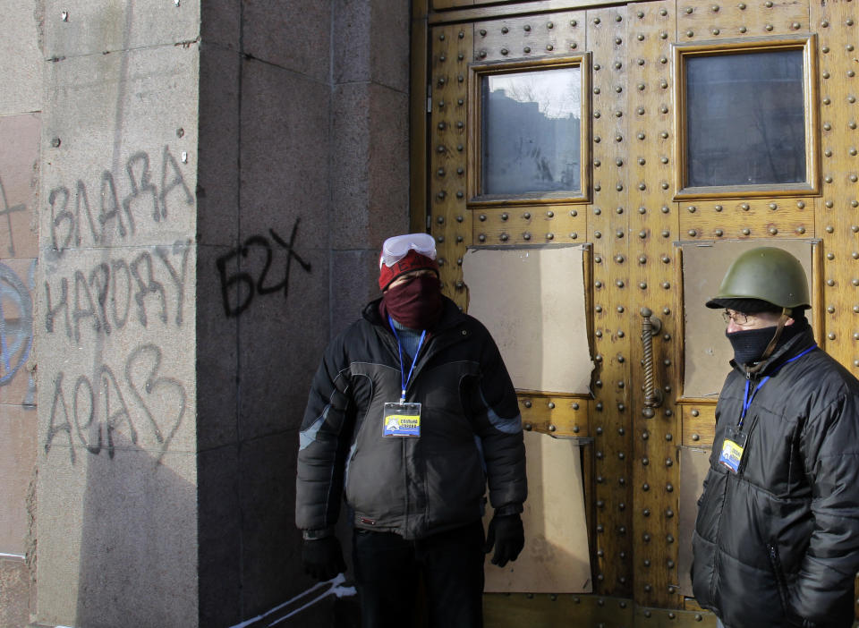 Pro-European Union activists guard the doors of the Ministry of Agricultural Policy building, in Kiev, Ukraine, Friday Jan. 24, 2014. Graffiti reads: "Government for people". Protesters on Friday seized a government building in the Ukrainian capital while also maintaining the siege of several governors’ offices in the country’s west, raising the pressure on the government. (AP Photo/Darko Vojinovic)