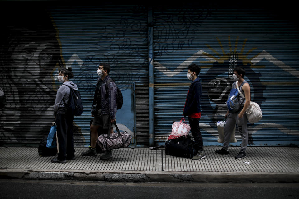 People line up to get their temperature checked before being allowed into a bus to return to their provinces in Buenos Aires, Argentina, Wednesday, April 1, 2020. The Argentine government ordered a forced lock down to help contain the spread of the new coronavirus. (AP Photo/Natacha Pisarenko)