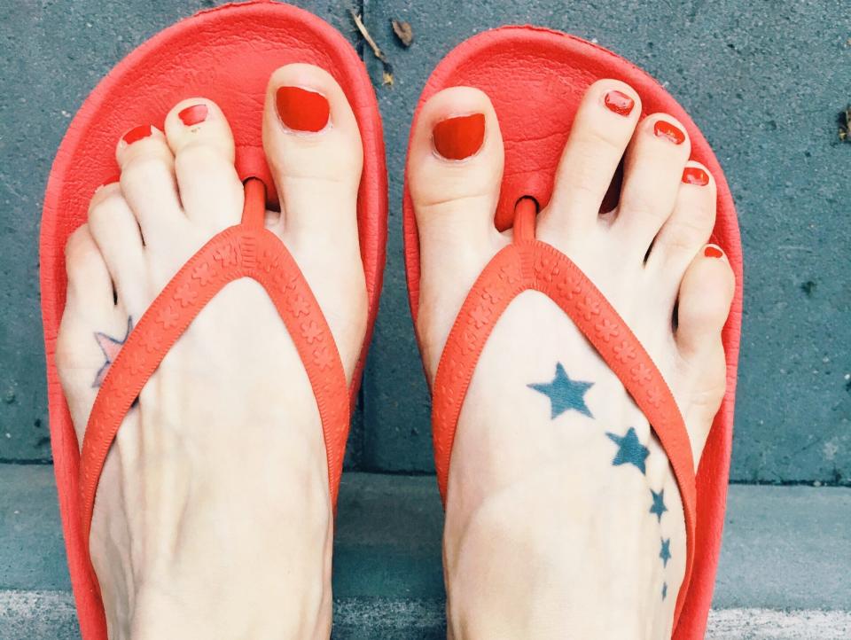 feet in red lip flops with stars tattooed on foot