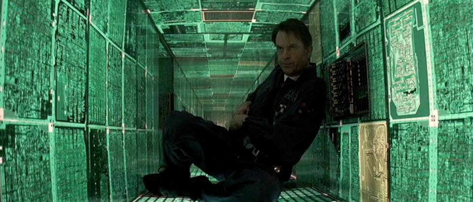 Sam Neill sits in a small green crawlspace.