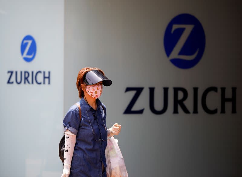 A woman wearing a protective face mask walks past in front of a office building of the Japanese unit of Zurich Insurance Group during a nationwide state of emergency in Tokyo, as the spread of the coronavirus disease (COVID-19) continues in Japan