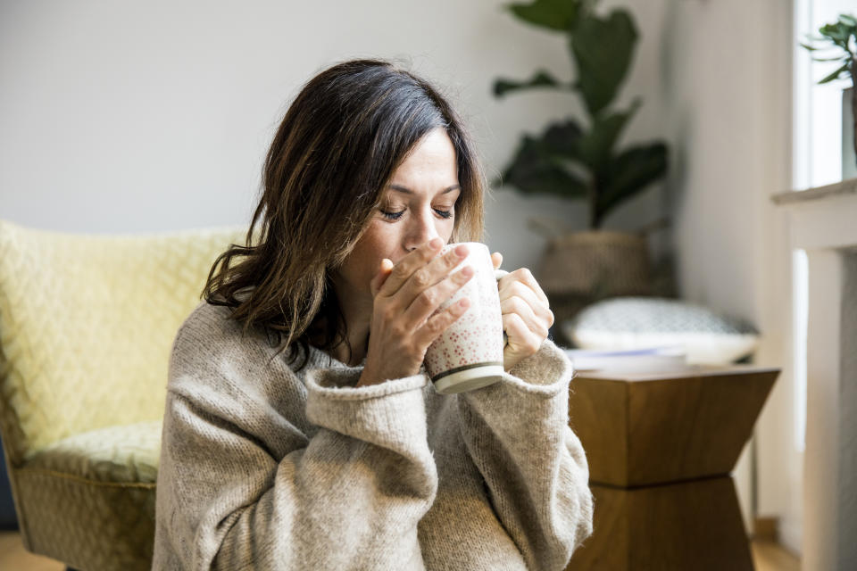 Woman sitting in her comfortable home, drinking tea