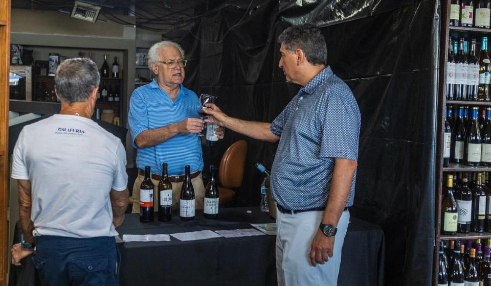 Michael Bittel (centro), antiguo copropietario de Sunset Corners, organizó catas de vino en el negocio durante décadas. El 1 de junio de 2024 sirve vino al nuevo propietario, Eduardo Cruz, que compró la tienda de vinos finos y licores y la rebautizó como Jensen's at Sunset Corners. Bittel continuará con estas catas de vino.