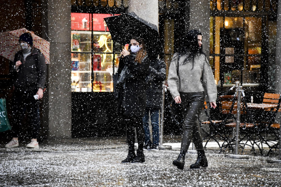 A woman wearing a face mask takes a photo on her phone in Covent Garden, London, Thursday, Dec. 3, 2020. Britain became the first country in the world to authorize a rigorously tested COVID-19 vaccine Wednesday and could be dispensing shots within days — a historic step toward eventually ending the outbreak that has killed more than 1.4 million people around the globe. (AP Photo/Alberto Pezzali)