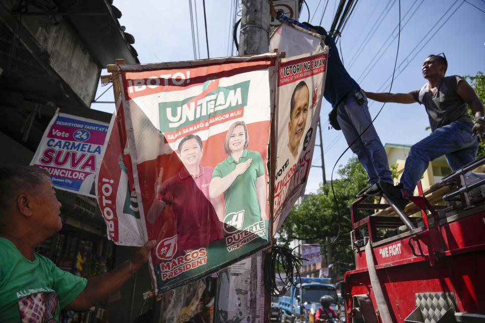 Village workers remove a campaign poster showing Presidential candidate Ferdinand "Bongbong" Marcos Jr. and running mate Sara Duterte along a street in Quezon city, Philippines on Wednesday, May 11, 2022. Marcos, the namesake son of longtime dictator Ferdinand Marcos, apparent landslide victory in the Philippine presidential election is raising immediate concerns about a further erosion of democracy in Asia and could complicate American efforts to blunt growing Chinese influence and power in the Pacific. (AP Photo/Aaron Favila)