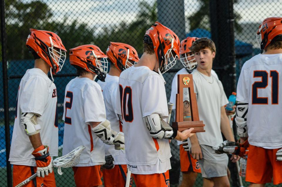 Benjamin's Ford Cash gingerly holds the prized district trophy following the Bucs' win over St. Edward's in the championship game on April 17, 2024.