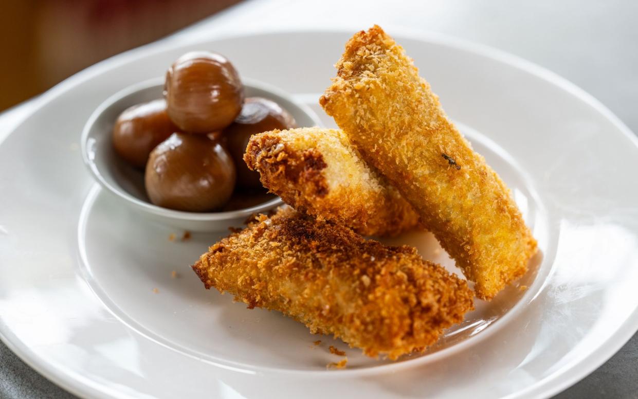 Deep-fried smoked haddocks rabbits on a white plate served with a bowl of pickled onions