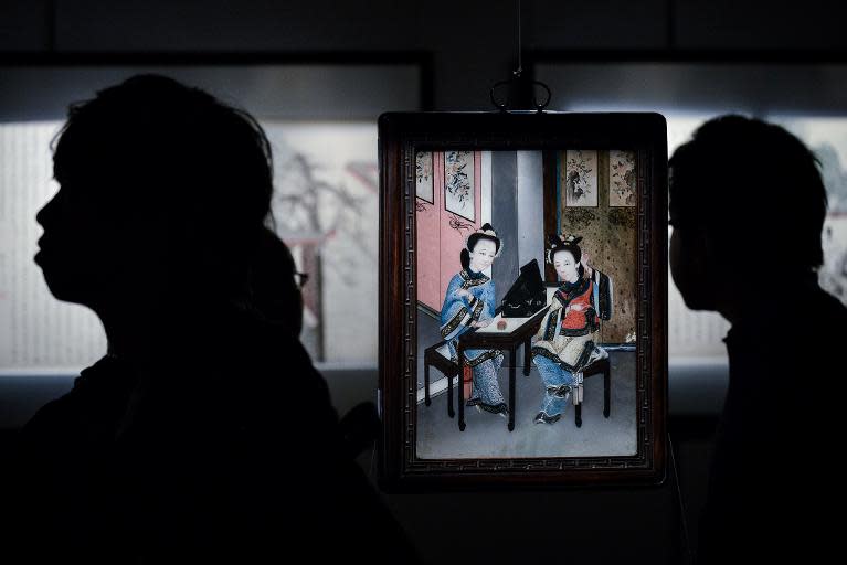 Visitors walk past a painted glass, part of the exhibition 'Gardens of Pleasure: Sex in Ancient China', in Hong Kong, on April 15, 2014