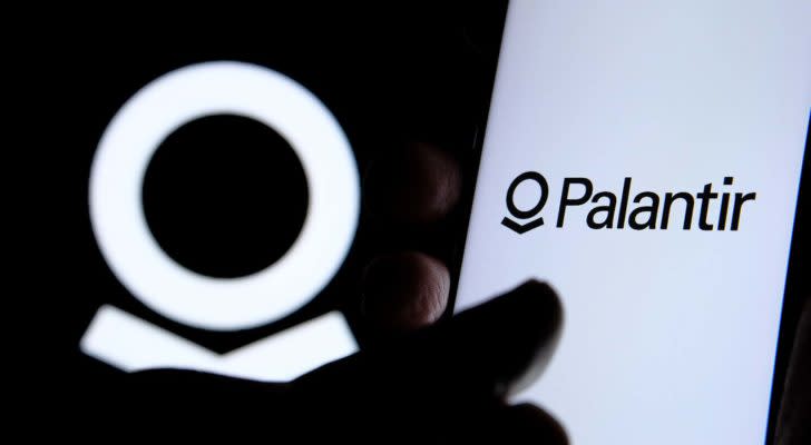 A close-up shot of a hand on a screen with the Palantir (PLTR) logo.