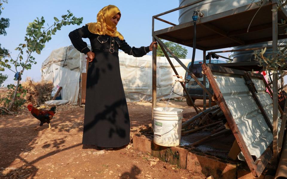 La refugiada siria Hidaya Mohammad Daoud recoge agua de un tanque en el asentamiento informal de Mqaitaa, donde vive con su familia en el norte del Líbano.  Dos de sus hijos actualmente muestran signos de cólera, mientras que otro fue hospitalizado recientemente con la enfermedad.  - ELISA ODDONE