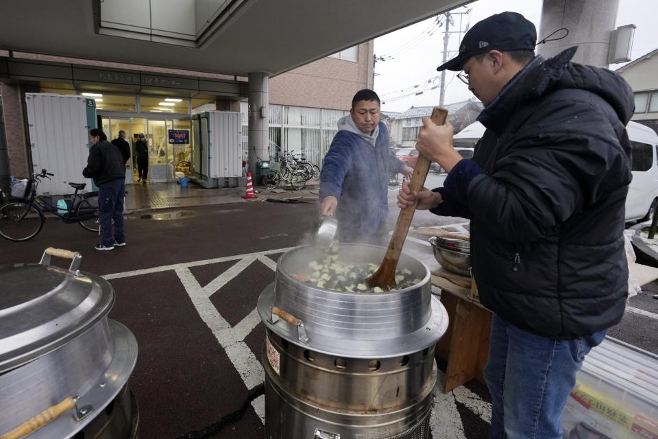 Evacuees prepare hot meals to disaster victims at an evacuation center in Wajima in the Noto peninsula facing the Sea of Japan, northwest of Tokyo, Sunday, Jan. 7, 2024. Monday's temblor decimated houses, twisted and scarred roads and scattered boats like toys in the waters, and prompted tsunami warnings. (AP Photo/Hiro Komae)