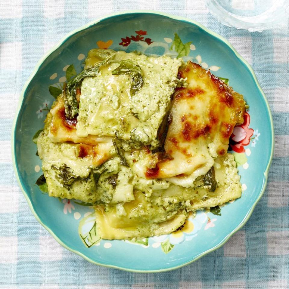 baked spinach ravioli with pesto cream sauce in blue bowl