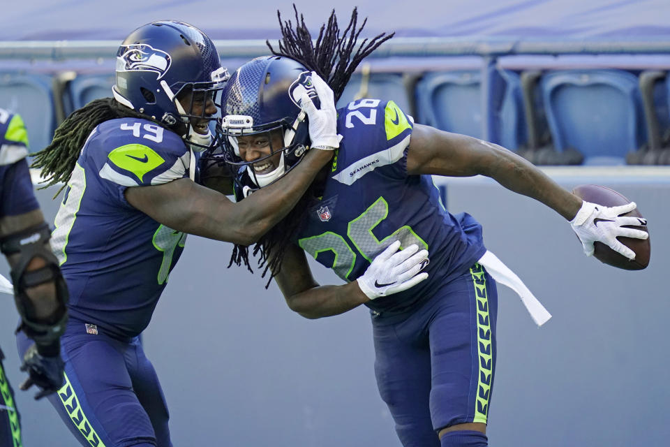 Seattle Seahawks cornerback Shaquill Griffin (26) is greeted by his twin brother, outside linebacker Shaquem Griffin (49), after Shaquill Griffin intercepted a pass against the Dallas Cowboys during the first half of an NFL football game, Sunday, Sept. 27, 2020, in Seattle. (AP Photo/Elaine Thompson)