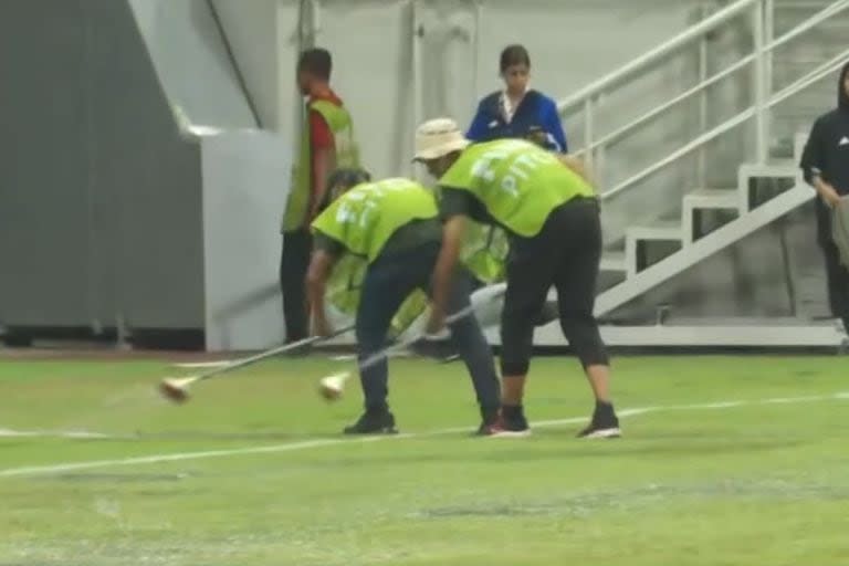 Auxiliares sacan agua del terreno de juego con secadores en el estadio Internacional de Yakarta, en Indonesia, donde se disputa el Mundial Sub 17