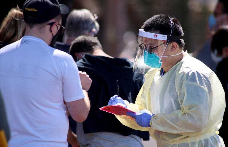 Medical staff taking details from people who are queuing at the Covid-19 Testing facility at Parafield Airport in Adelaide.