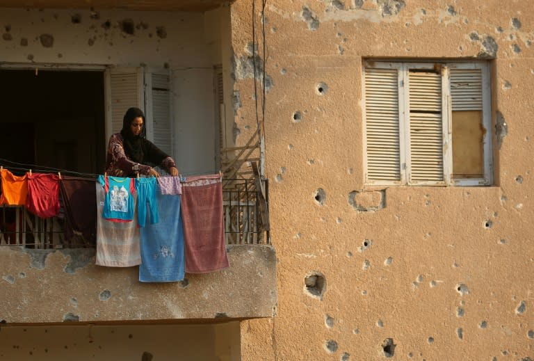 A displaced woman who fled the Islamic State group's Syrian stronghold of Raqa hangs laundry at a shrapnel riddled abandoned building in the town of Tabqa