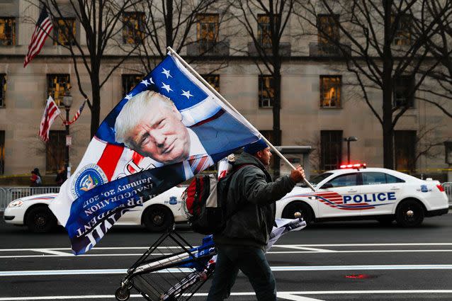 A street vendor holds a flag bearing the likeness of President-elect Donald Trump on Pennsylvania Avenue in Washington DC. Source: AP