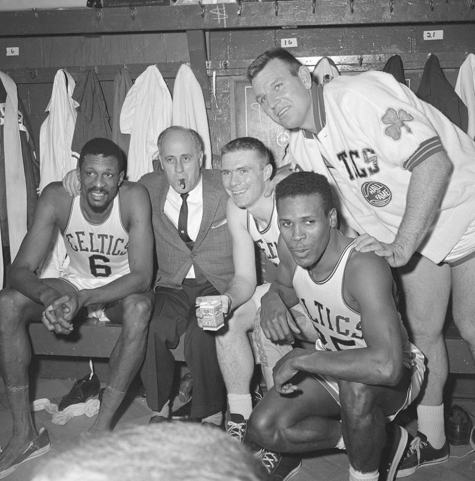In this April 9, 1964, file photo, Boston Celtics, from left, Bill Russell, coach Red Auerbach, Tommy Heinsohn, Jim Locustoff, and K.C. Jones celebrate in the locker room after clinching their eighth straight Eastern Division playoff title at the Boston Garden in Boston. (AP Photo, File)