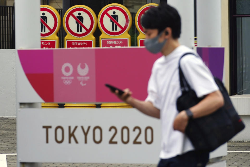 A man wearing a protective mask to help curb the spread of the coronavirus walks past a banner for the Tokyo 2020 Olympic and Paralympic Games on May 11, 2021, in Tokyo. The Japanese government was quick to respond on Tuesday, May 25, 2021 to U.S. travel warning for Americans against traveling to Japan and denied impact on Olympic participants, as the country determinedly prepare to host the postponed games in two months. (AP Photo/Eugene Hoshiko)