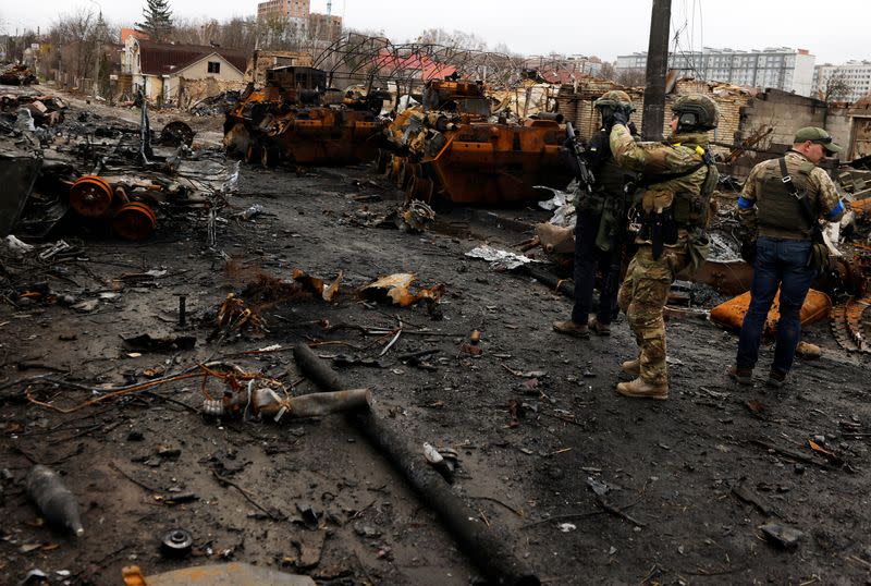 A serviceman uses his mobile phone to film a destroyed Russian tank and armoured vehicles, amid Russia's invasion on Ukraine in Bucha, in Kyiv region