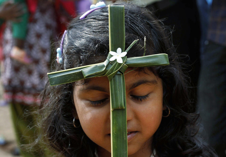 An Indian Christian girl holds a cross made of blessed palm during a Palm Sunday mass at a church in Bhubaneswar, India, Sunday, April 13, 2014. Palm Sunday's liturgy recalls Jesus' triumphant entry into Jerusalem. (AP Photo/Biswaranjan Rout)