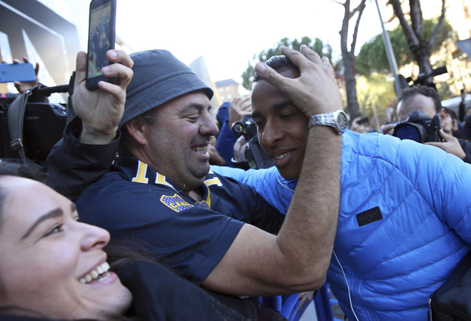 Boca Juniors' Sebastian Villa, right, is hugged by a supporter as the team arrives at their hotel in Madrid Saturday, Dec. 8, 2018. The Copa Libertadores Final between River Plate and Boca Juniors will be played on Dec. 9 in Madrid, Spain, at Real Madrid's stadium. (AP Photo/Andrea Comas)