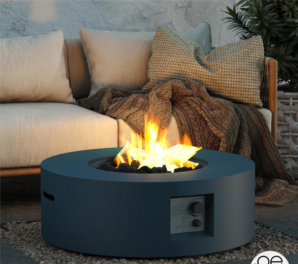 circular dark gray lit fire pit next to neutral-tone patio furniture