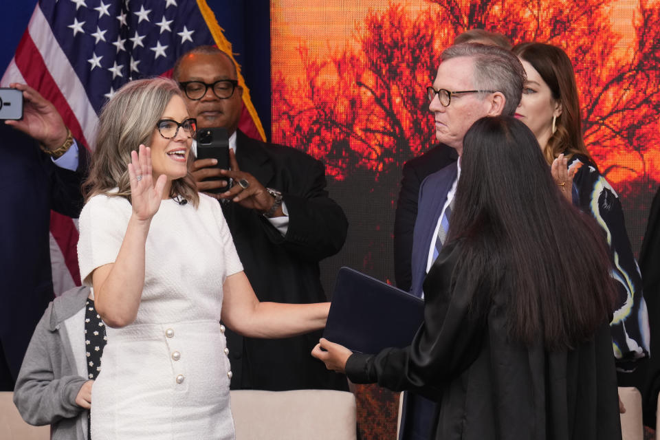 Arizona Democratic Gov. Katie Hobbs, left, takes the ceremonial oath of office during a public inauguration as husband Patrick Goodman, second from right, looks on as U.S. Circuit Judge for the Ninth Circuit Court of Appeals Roopali Desai, right, performs the oath at the state Capitol in Phoenix, Thursday, Jan. 5, 2023. (AP Photo/Ross D. Franklin)