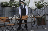A waiter prepares tables and chairs in an outdoor dining area in London, Thursday, Sept. 24, 2020, after Britain's Prime Minister Boris Johnson announced a range of new restrictions to combat the rise in coronavirus cases in England. (AP Photo/Kirsty Wigglesworth)