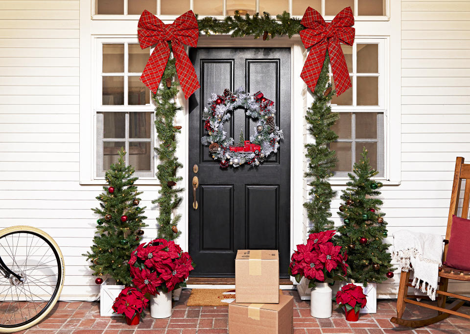 This image provided by Lowe's shows a traditional front door decoration. Frame the front door or wrap a railing with a lighted garland, and add a coordinating wreath, for a cozy, festive vibe. There are plug-in versions as well as battery operated ones, with a timer – great if you have no handy plug. www.lowes.com (Lowe's via AP)