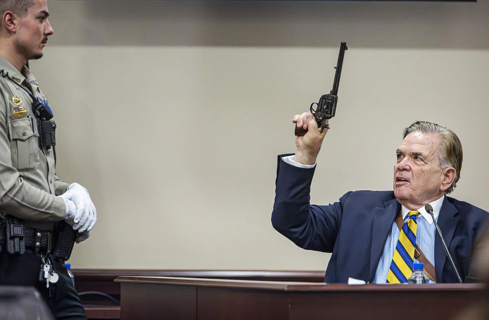 Santa Fe County Deputy Levi Abeyta, left, watches as expert witness for the defense Frank Koucky III demonstrates how to uncock a gun like the one used on the set of the movie "Rust" as Koucky testifies in the involuntary manslaughter trial of movie armorer Hannah Gutierrez-Reed, Tuesday, March 5, 2024, at the First Judicial District Courthouse in Santa Fe, N.M. (Jim Weber/Santa Fe New Mexican via AP, Pool)