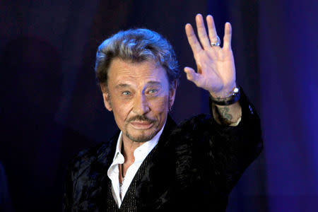 FILE PHOTO: French singer Johnny Hallyday waves to fans attending a ceremony to promote his new album "Jamais seul" (Never alone) at the Virgin Megastore in Paris early March 28, 2011. REUTERS/Charles Platiau/File Photo