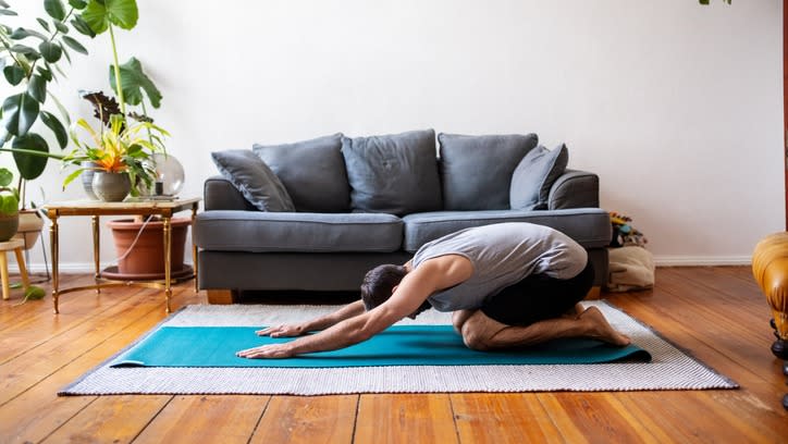  Man doing child's pose in his living room 