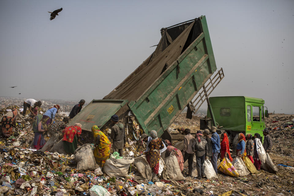 Trash pickers surround a municipal garbage truck dumping trash at the Bhalswa landfill on the outskirts of New Delhi, India, Wednesday, March 10, 2021. The pandemic has amplified the risks that these informal workers face. Few have their own protective gear or even clean water to wash their hands, said Chitra Mukherjee of Chintan, a nonprofit environmental research group in New Delhi. (AP Photo/Altaf Qadri)