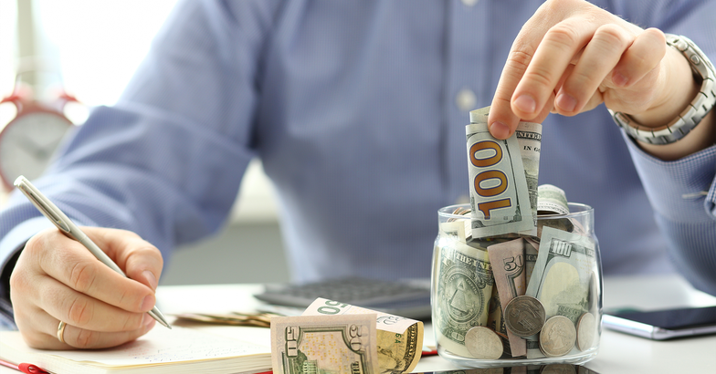 man putting money into savings jar