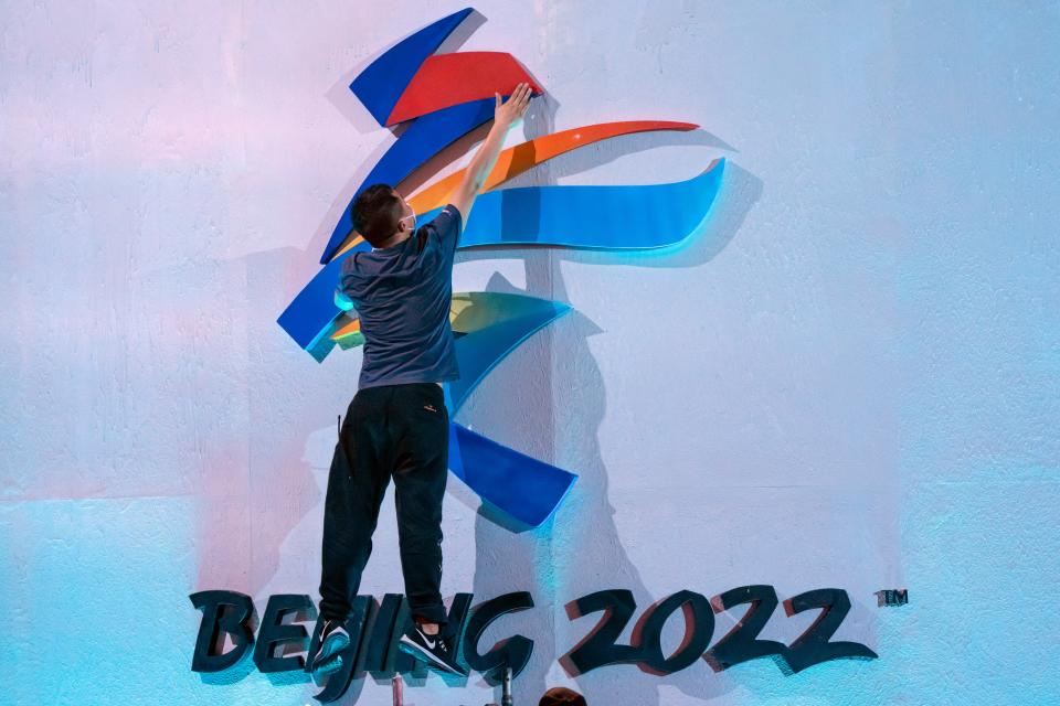 A crew member leaps to fix a logo for the 2022 Beijing Winter Olympics.