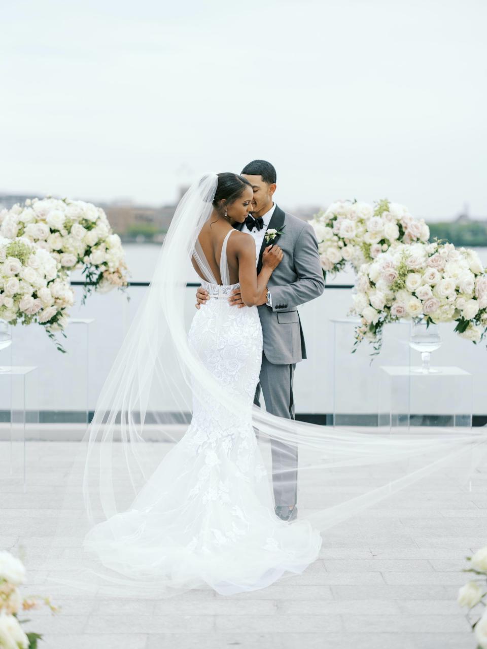 A bride hugs her groom as her veil flies behind her.