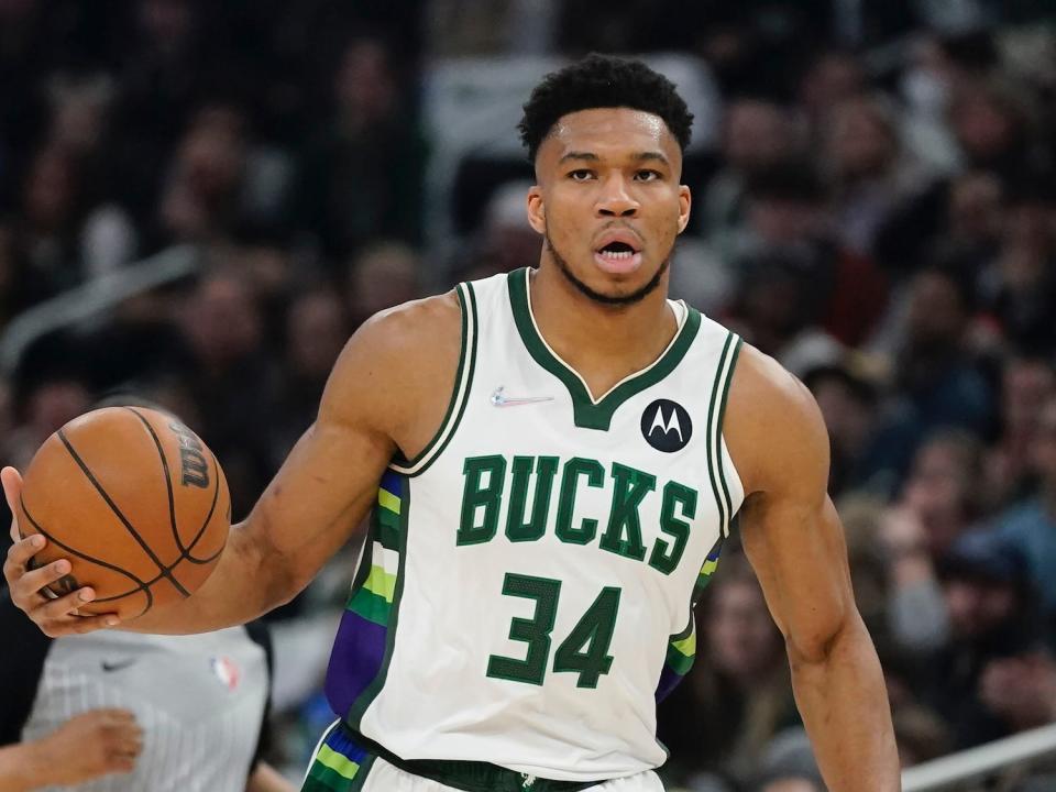 Giannis Antetokounmpo dribbles the ball while scanning the floor.