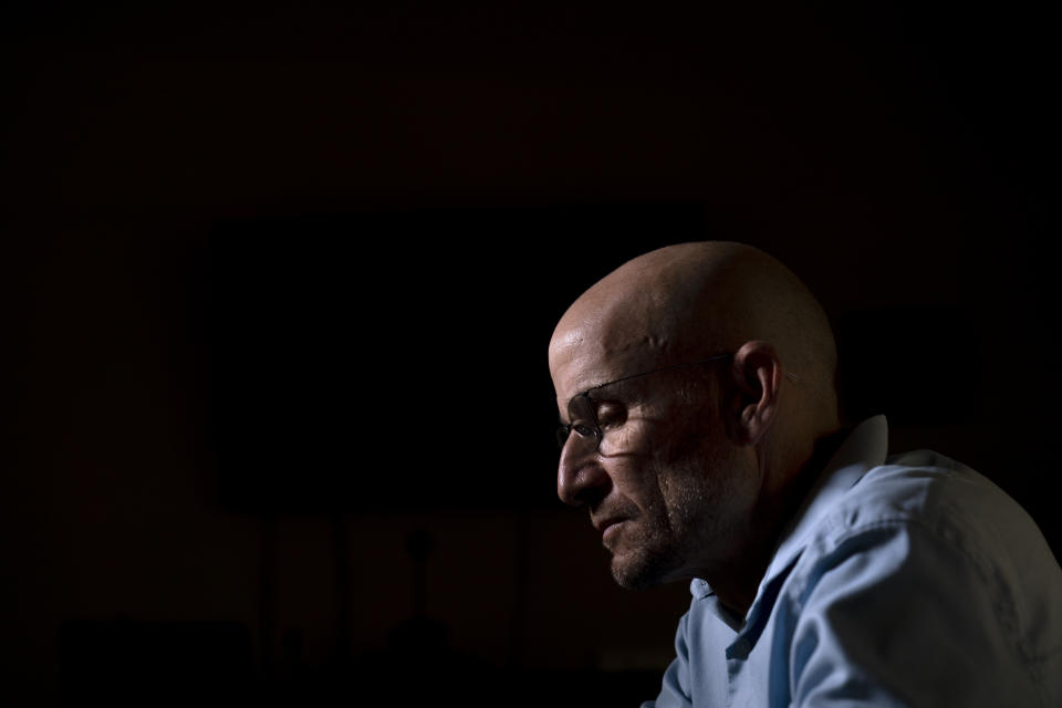 Harry Bruell looks at photos of his daughter, Taya, saved in his smartphone while sitting for a photo in his office in Santa Barbara, Calif., Wednesday, March 9, 2022. Taya killed herself when she was 14. (AP Photo/Jae C. Hong)