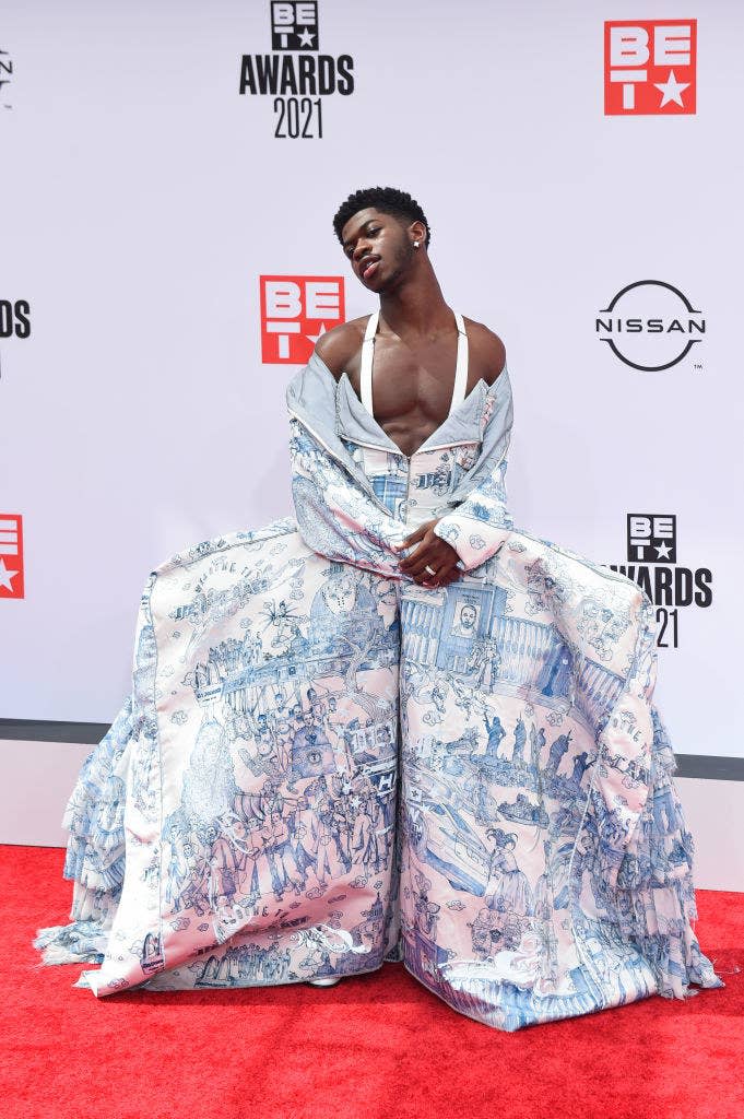 Lil Nas poses on a red carpet in a printed off-shoulder ball gown