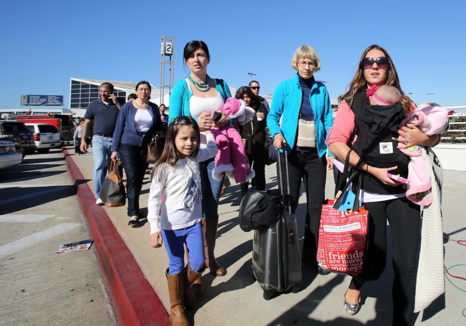 Passengers evacuate the Los Angeles International Airport on Friday Nov. 1, 2013, after shots were fired prompting authorities to evacuate a terminal and stop flights headed for the city from taking off from other airports. (AP Photo/Ringo H.W. Chiu)