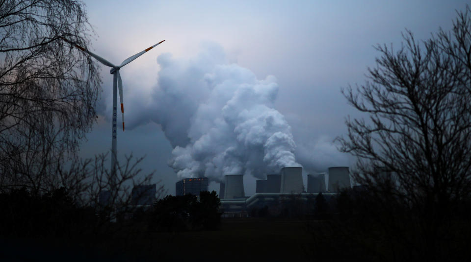 FILE PHOTO: Water vapour rises from the cooling towers of the Jaenschwalde lignite-fired power plant of Lausitz Energie Bergbau AG (LEAG) beside a wind turbine in Jaenschwalde