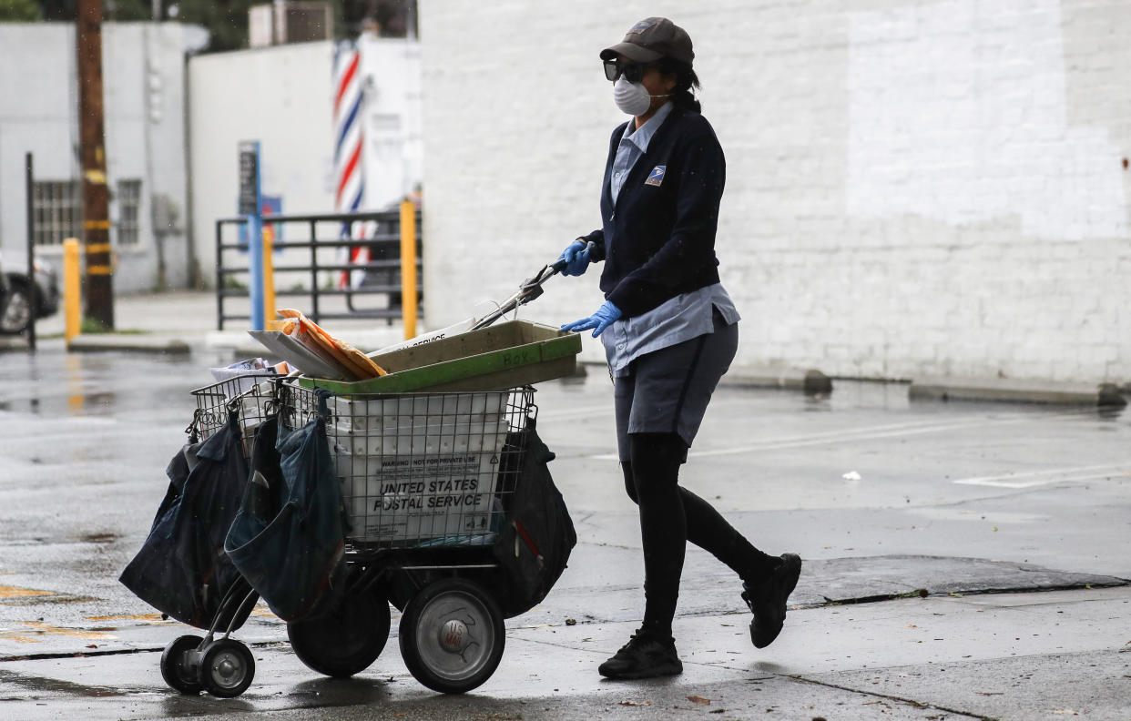 A U.S. Postal Service worker wears a mask and gloves