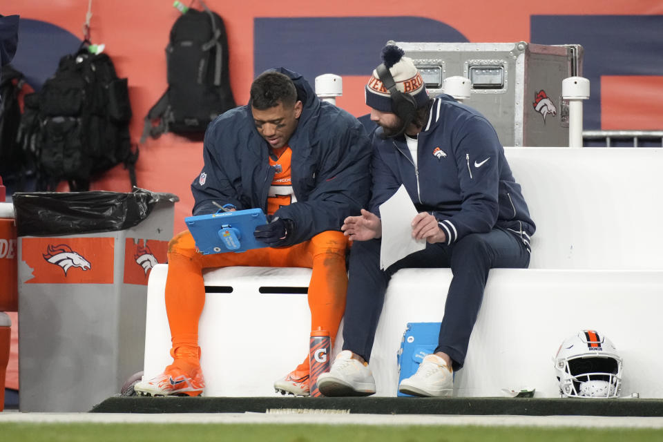 El quarterback de los Broncos de Denver Russell Wilson (izquierda) revisa jugadas durante la segunda mitad del juego de la NFL ante los Patriots de Nueva Inglaterra, el domingo 24 de diciembre de 2023, en Denver. (AP Foto/David Zalubowski)