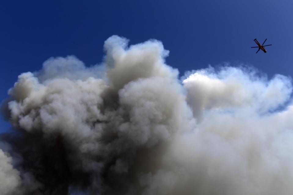 An helicopter operates during a wildfire in Tatoi area, northern Athens, Greece, Tuesday, Aug. 3, 2021. Hundreds of residents living near a forest area north of Athens fled their homes Tuesday as a wildfire reached residential areas as Greece grappled with its worst heatwave in decades. (AP Photo/Michael Varaklas)