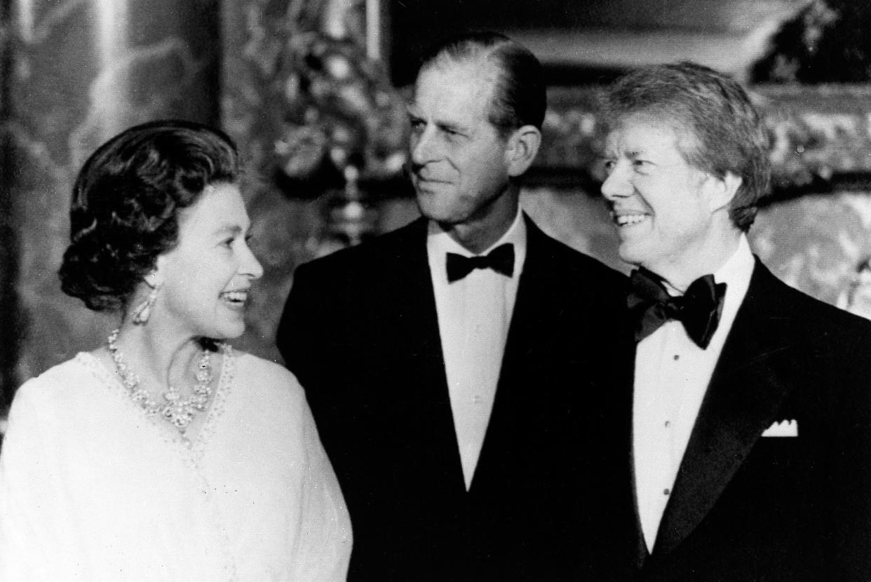 President Jimmy Carter, right, and Prince Philip, both wearing bow ties, pose with Queen Elizabeth II as she delivers an enthusiastic comment.