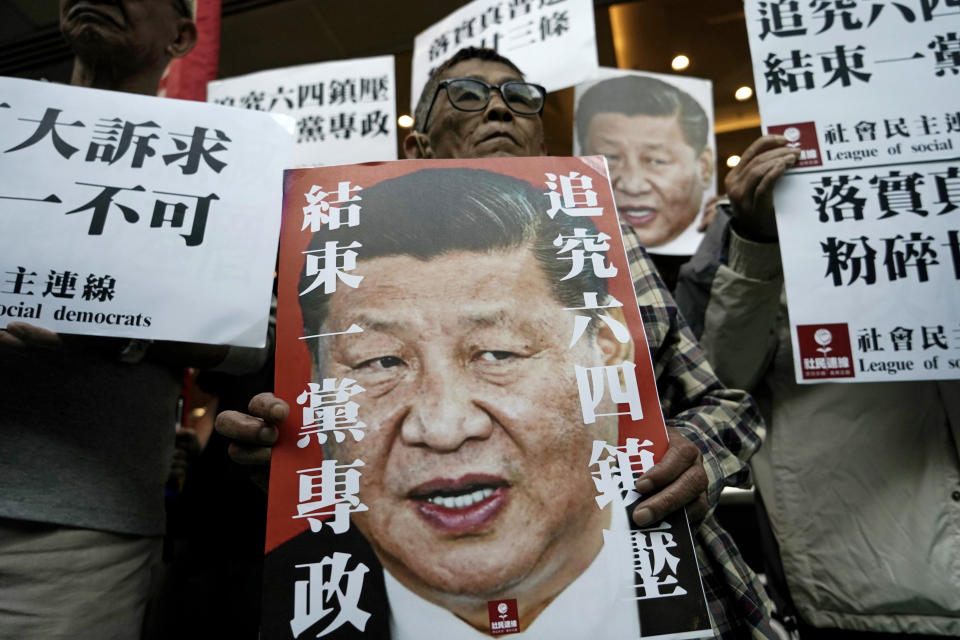 Pro-democracy activists hold up placards of Chinese President Xi Jinping at a ferry terminal in Hong Kong, Wednesday, Dec. 18, 2019. A ferry company barred a Hong Kong activist "Long Hair", whose real name is Leung Kwok-hung, from boarding a boat Wednesday to Macao, where Chinese President Xi Jinping is slated to arrive for the 20th anniversary of Macau's return to China, The placards read "Vindicate June 4th" and "Put an end to one-party Dictatorship". (AP Photo/Kin Cheung)