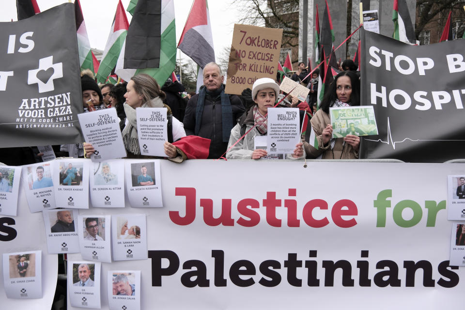 Protesters carry flags and banners outside the International Court of Justice in The Hague, Netherlands, Friday, Jan. 12, 2024. The United Nations' top court opened hearings Thursday into South Africa's allegation that Israel's war with Hamas amounts to genocide against Palestinians, a claim that Israel strongly denies. (AP Photo/Patrick Post)