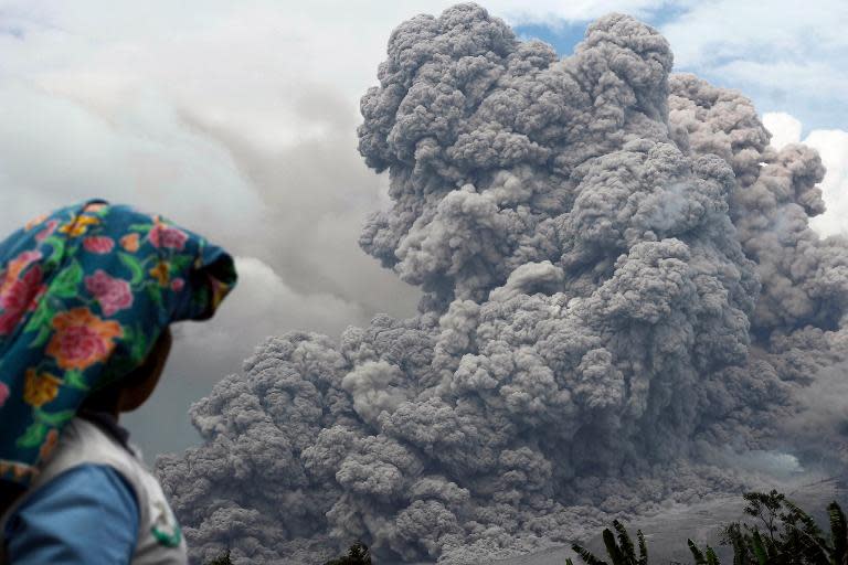 An Indonesian villager looks at Sinabung volcano as it spews hot ash in Karo on January 14, 2014