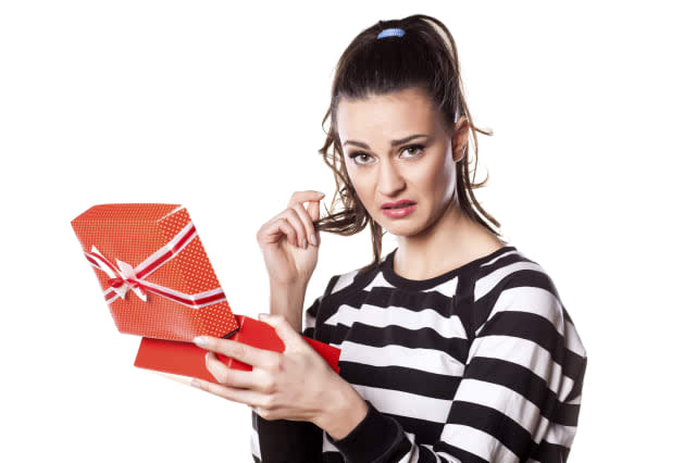 disappointed girl with questionable gesture holding a gift in her hand